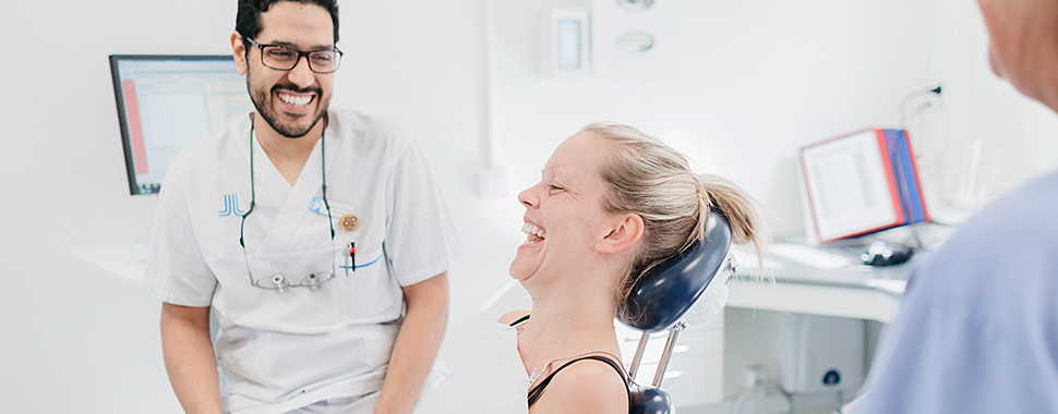 Tandläkare och patient skrattar tillsammans hos Folktandvården Stockholm.
