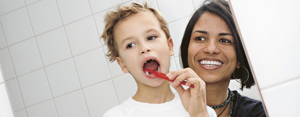 Mamma hjälper barn borsta tänderna efter råd från Folktandvården Stockholm.