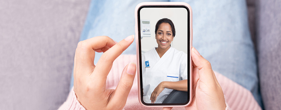 Patient har digitalt vårdmöte med tandläkare på Folktandvården Stockholm i sin mobil.