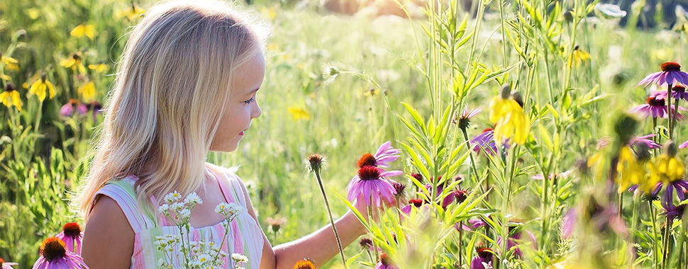 alt=”Foto på flicka på blomsteräng”